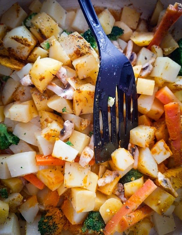 Seasoned vegetables arranged in a baking tin with oil and spices ready for the oven at 200 degrees