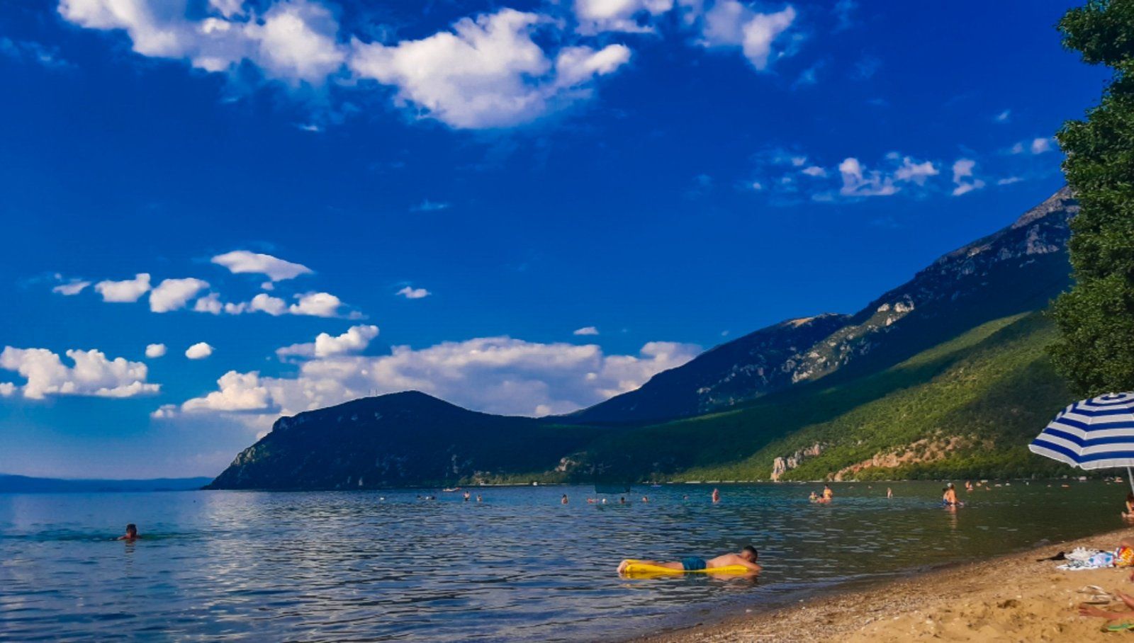 People swimming and splashing in the refreshing clear waters of Ohrid Lake on a hot summer day