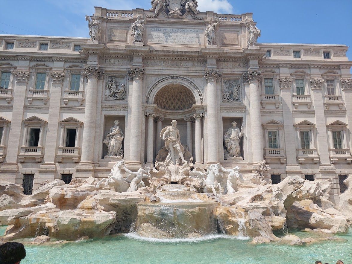 The Fontana Di Trevi illuminated at night with colorful water and the elegant travertine stone glowing
