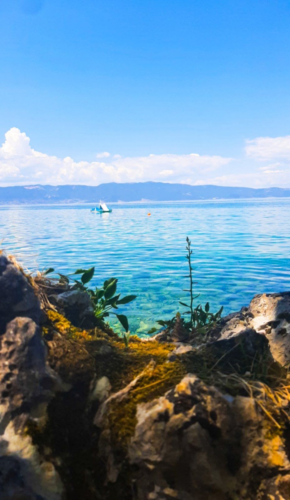 A cozy cafe table set beside the Ohrid Lake with coffee and a view of the endless blue water