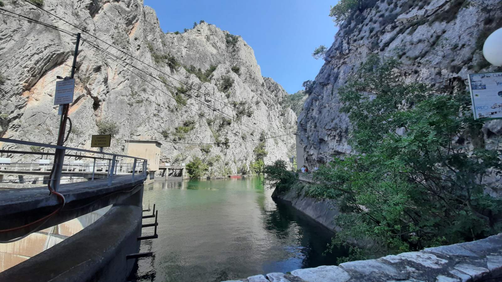 Boats docked along the calm emerald waters of Matka Lake surrounded by towering canyon walls
