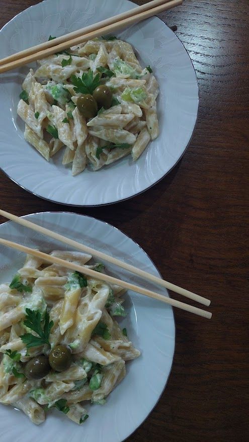 Delicious macaroni with broccoli cream sauce served on a plate with olives and parsley