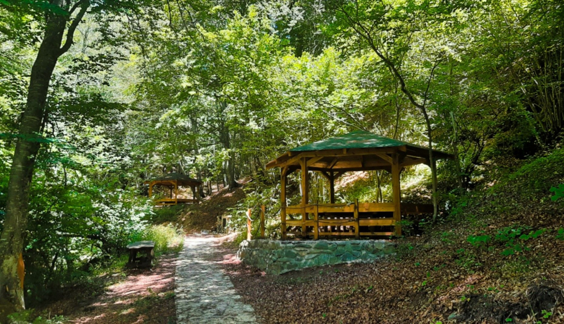 Wooden gazebos nestled among tall trees near the Crnodolski Waterfalls perfect for a peaceful picnic