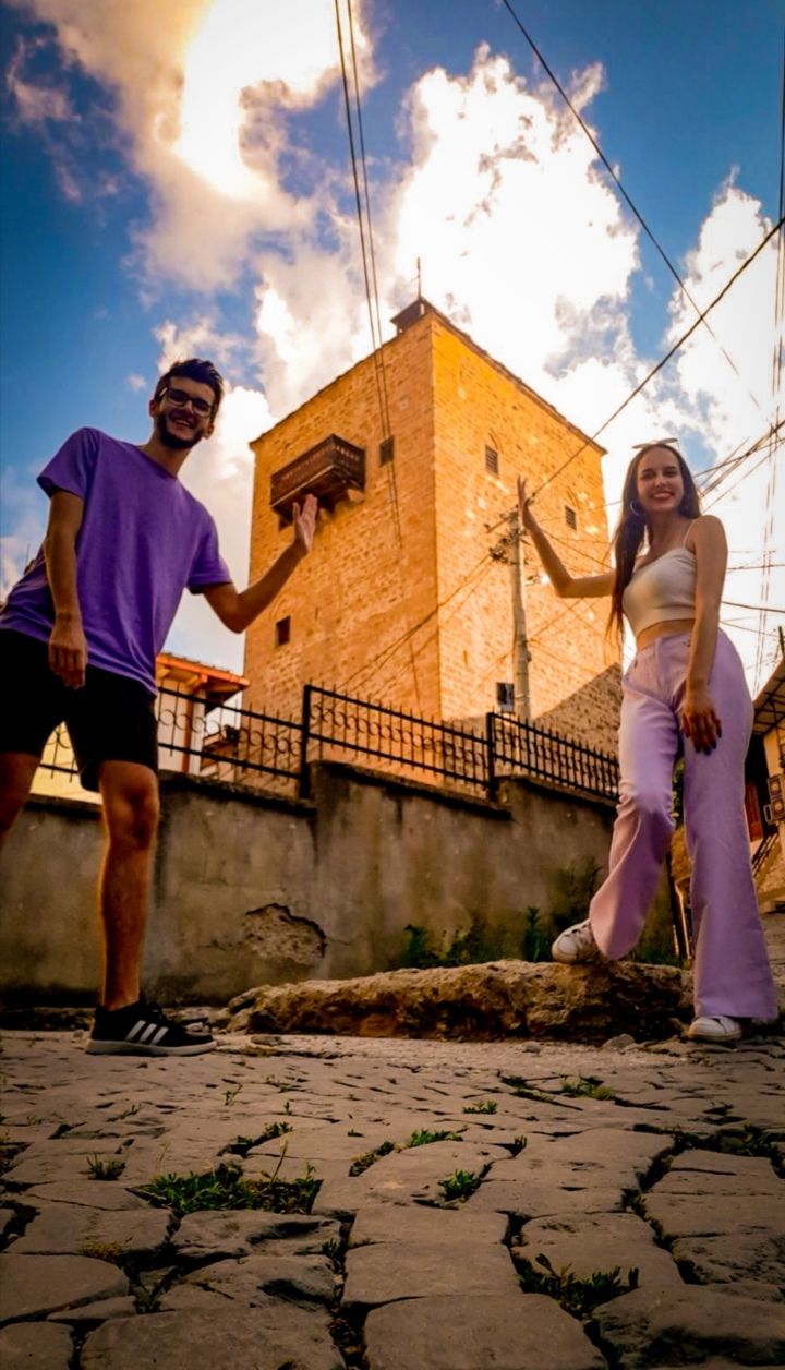 Two people playfully pretending to hold up one of the famous medieval towers of Kratovo Macedonia