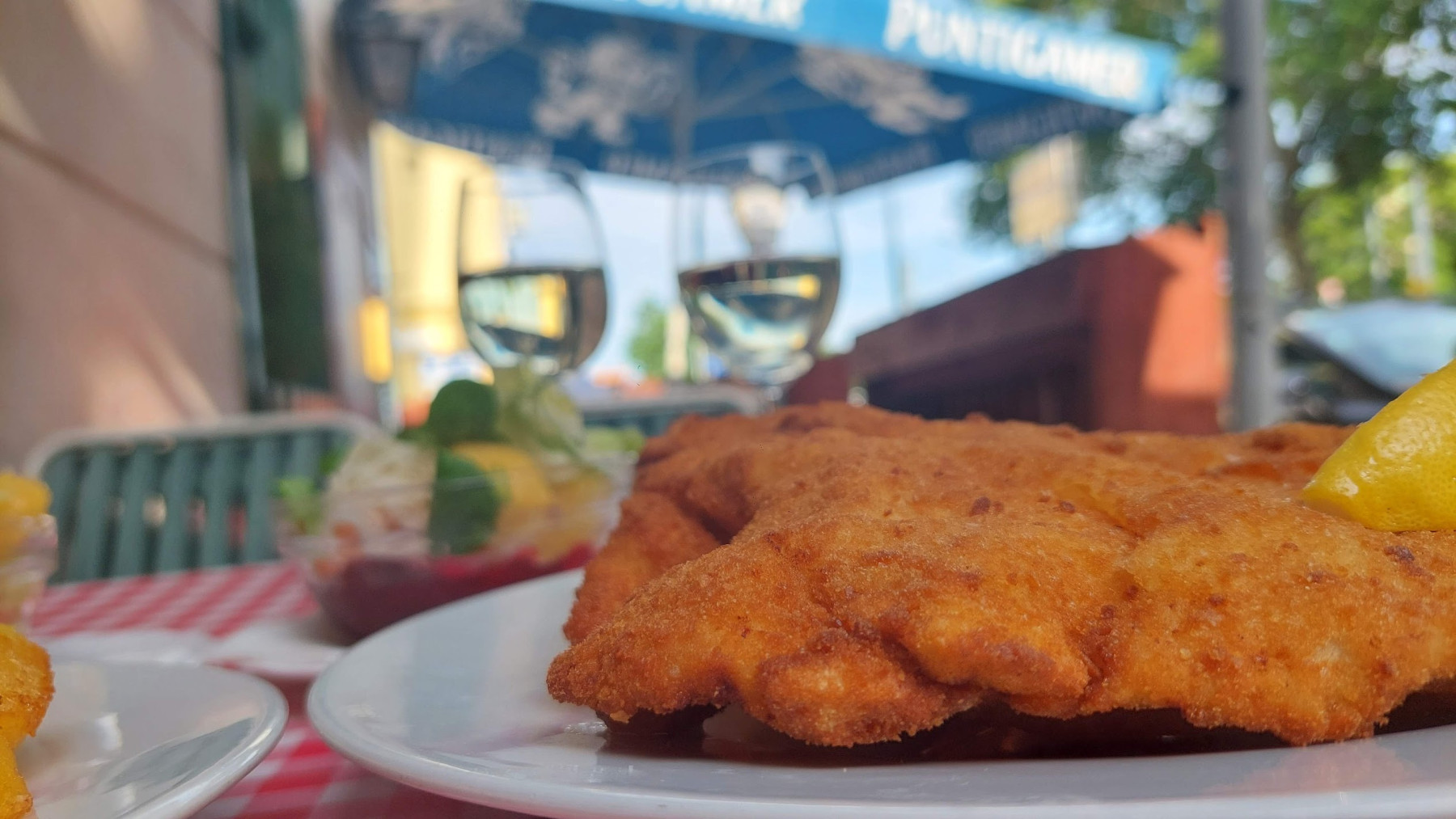A crispy Wiener Schnitzel with lemon served at an outdoor table in Vienna