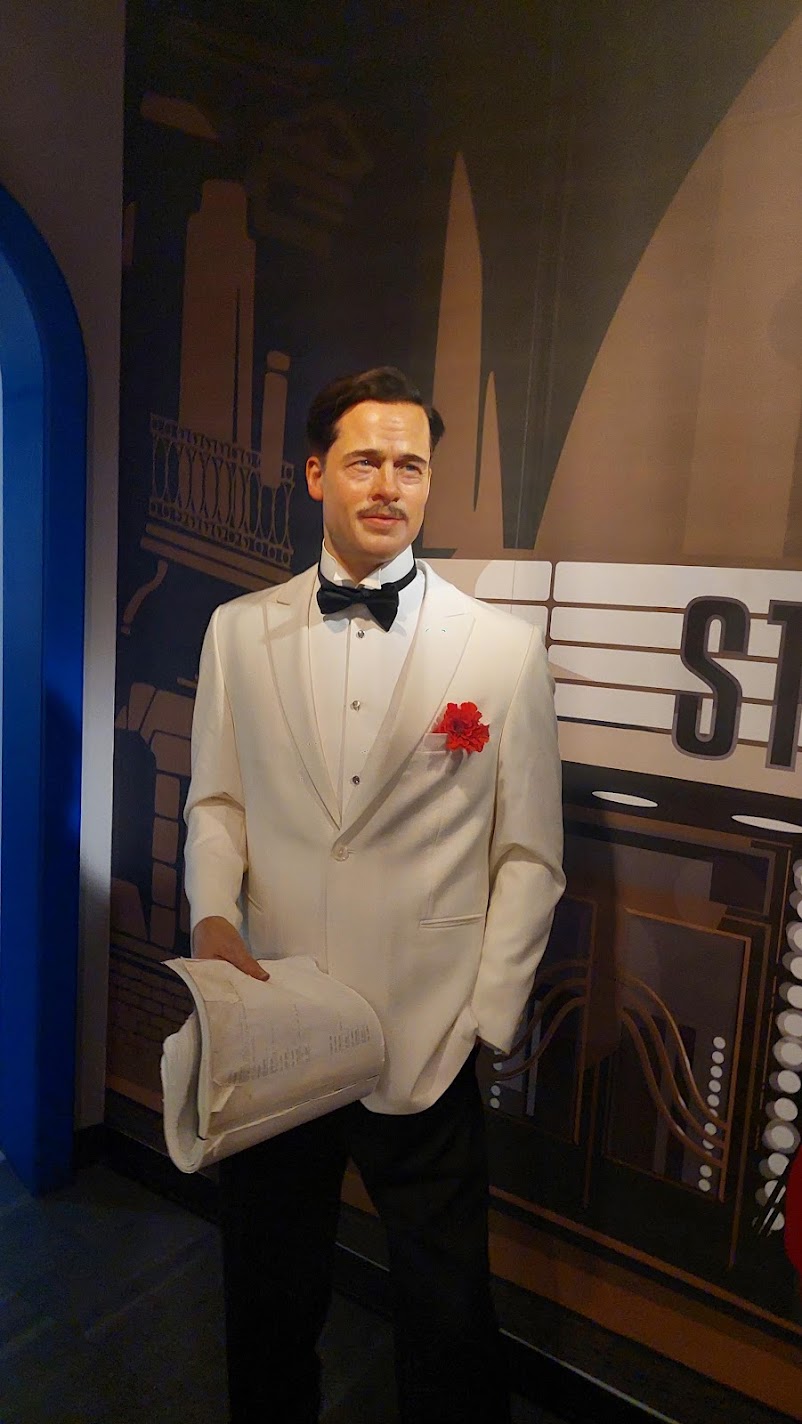 A wax figure in a white tuxedo holding a newspaper at Madame Tussauds in Vienna