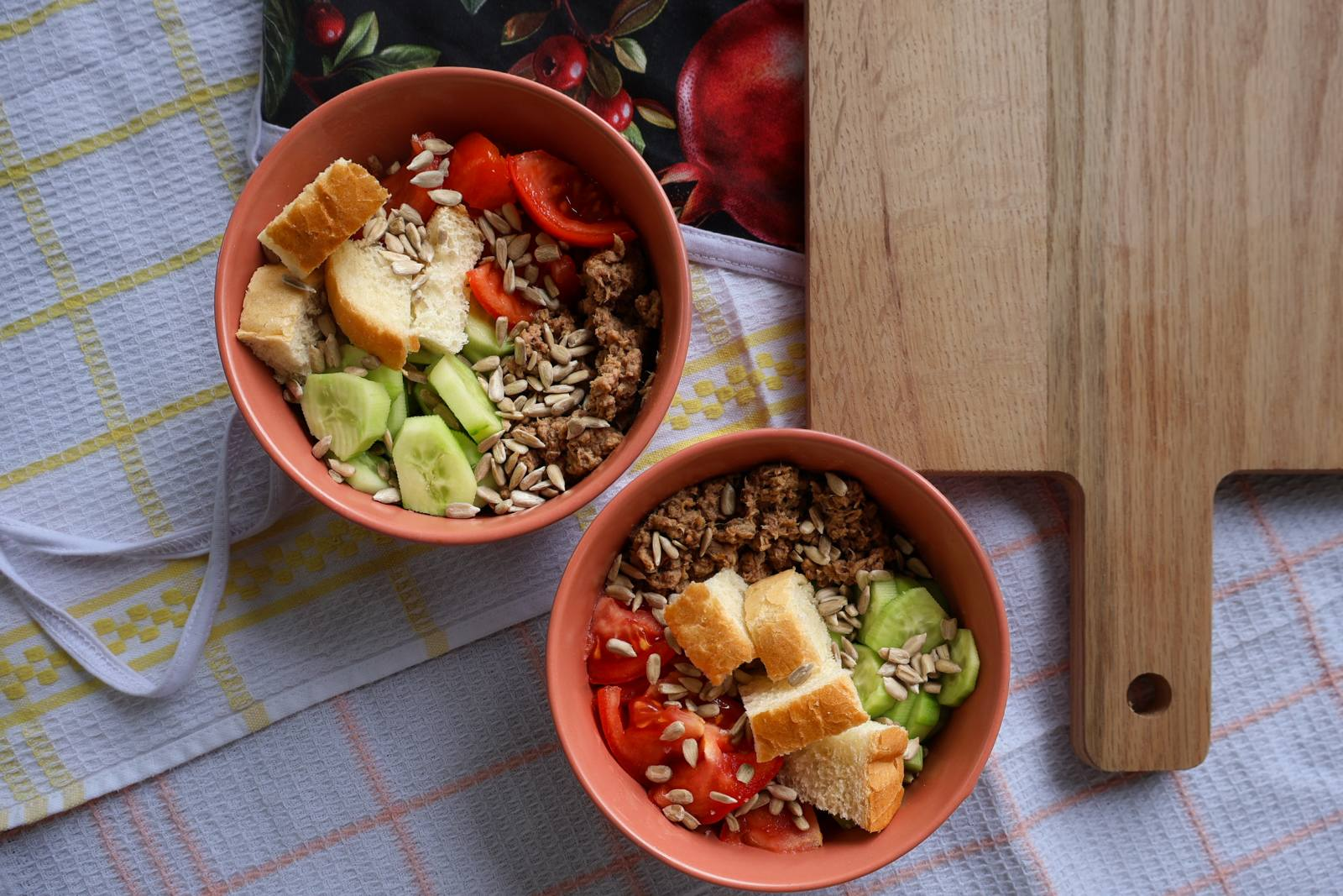 A breakfast bowl with tuna, tomato, cucumber, bread and sunflower seeds