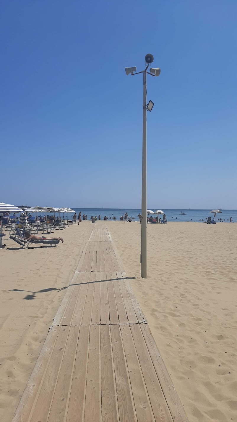 A wooden boardwalk crossing the sandy Lido Azzurro beach toward the Ionian Sea in Catania
