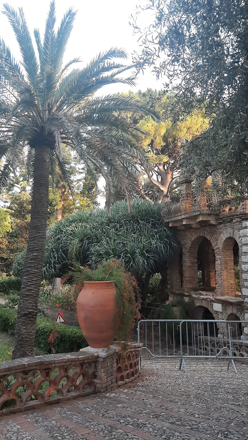 Palm trees and a terracotta urn in the terraced gardens of Villa Comunale in Taormina