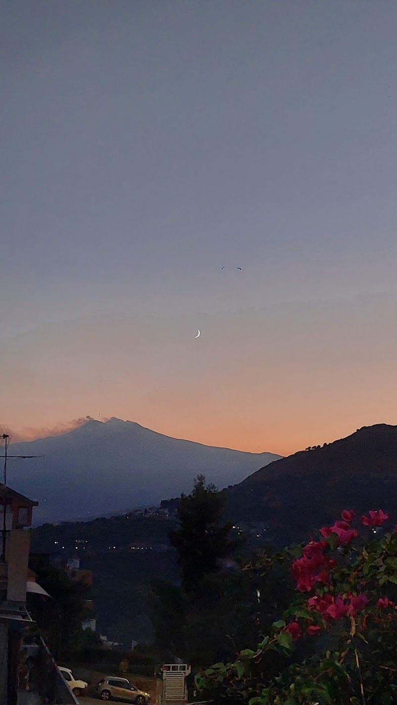 Mount Etna at sunset with a crescent moon above it, seen from Castelmola