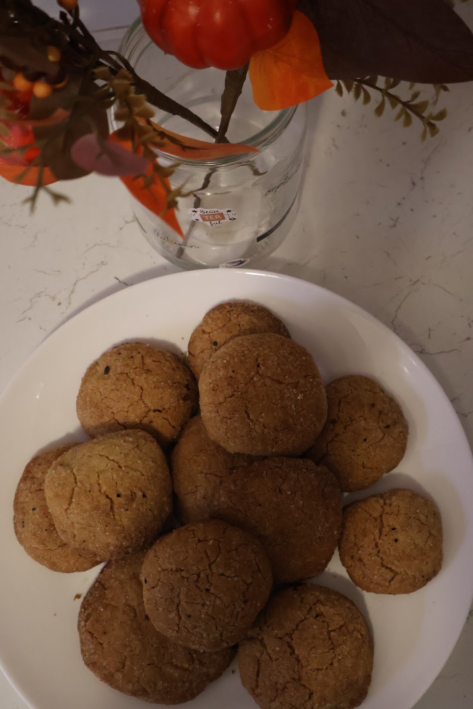 Crackled, sugar-coated pumpkin spice cookies on a white plate, seen from above