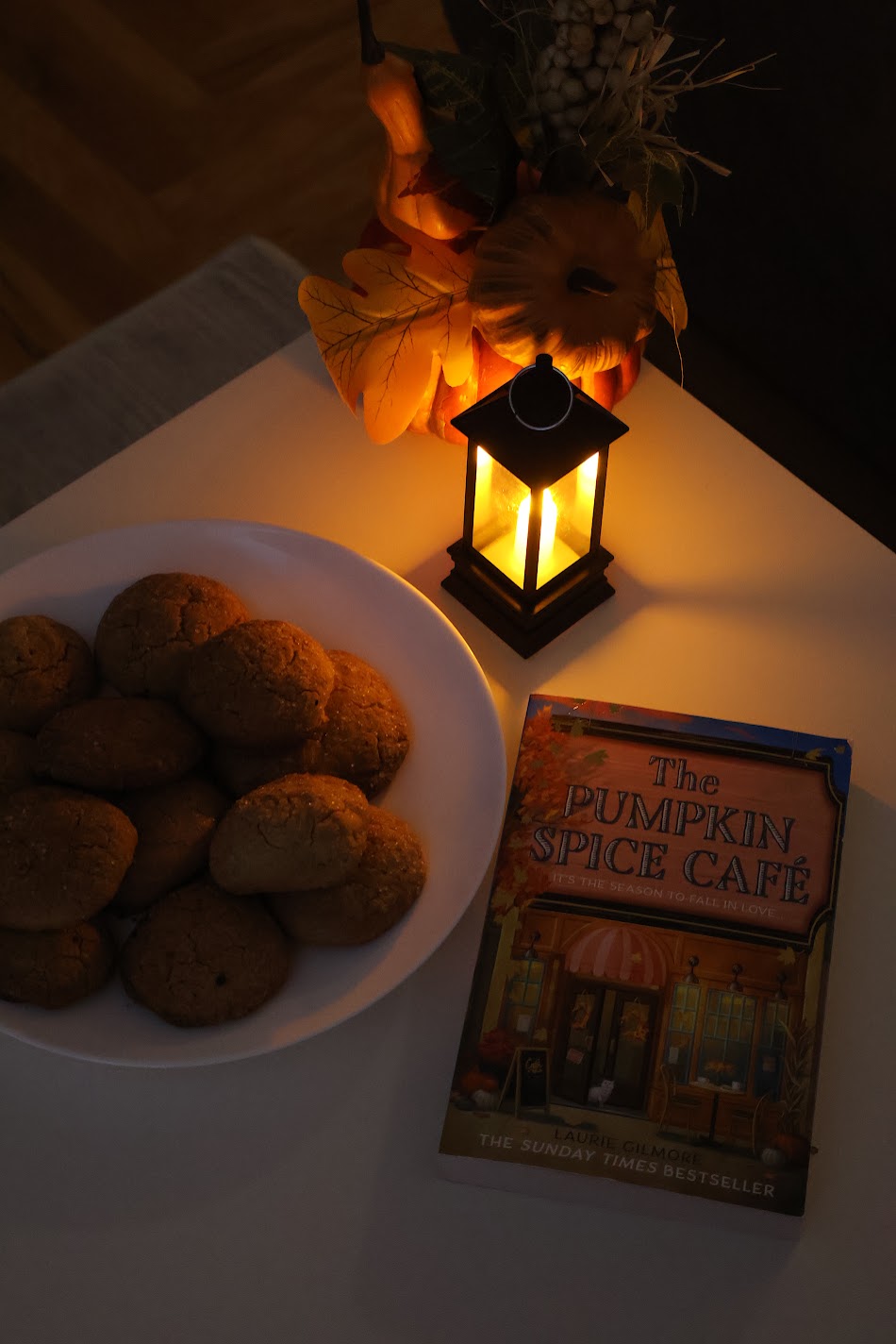 Pumpkin spice cookies by lantern light, next to the book The Pumpkin Spice Café