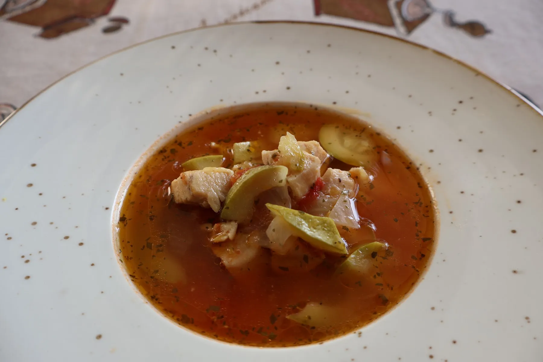 Chicken and courgette soup in a speckled white bowl