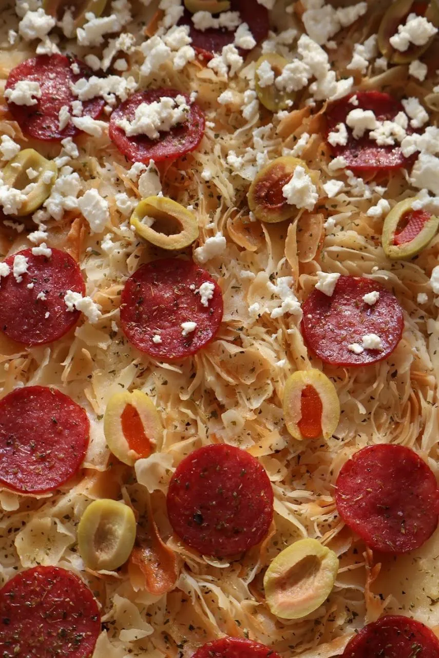 Close-up of a pizza with salami, stuffed olives and crumbled cheese