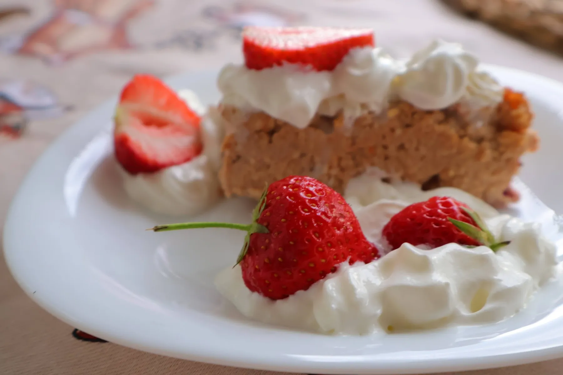 Slice of cake with whipped cream and fresh strawberries on a white plate