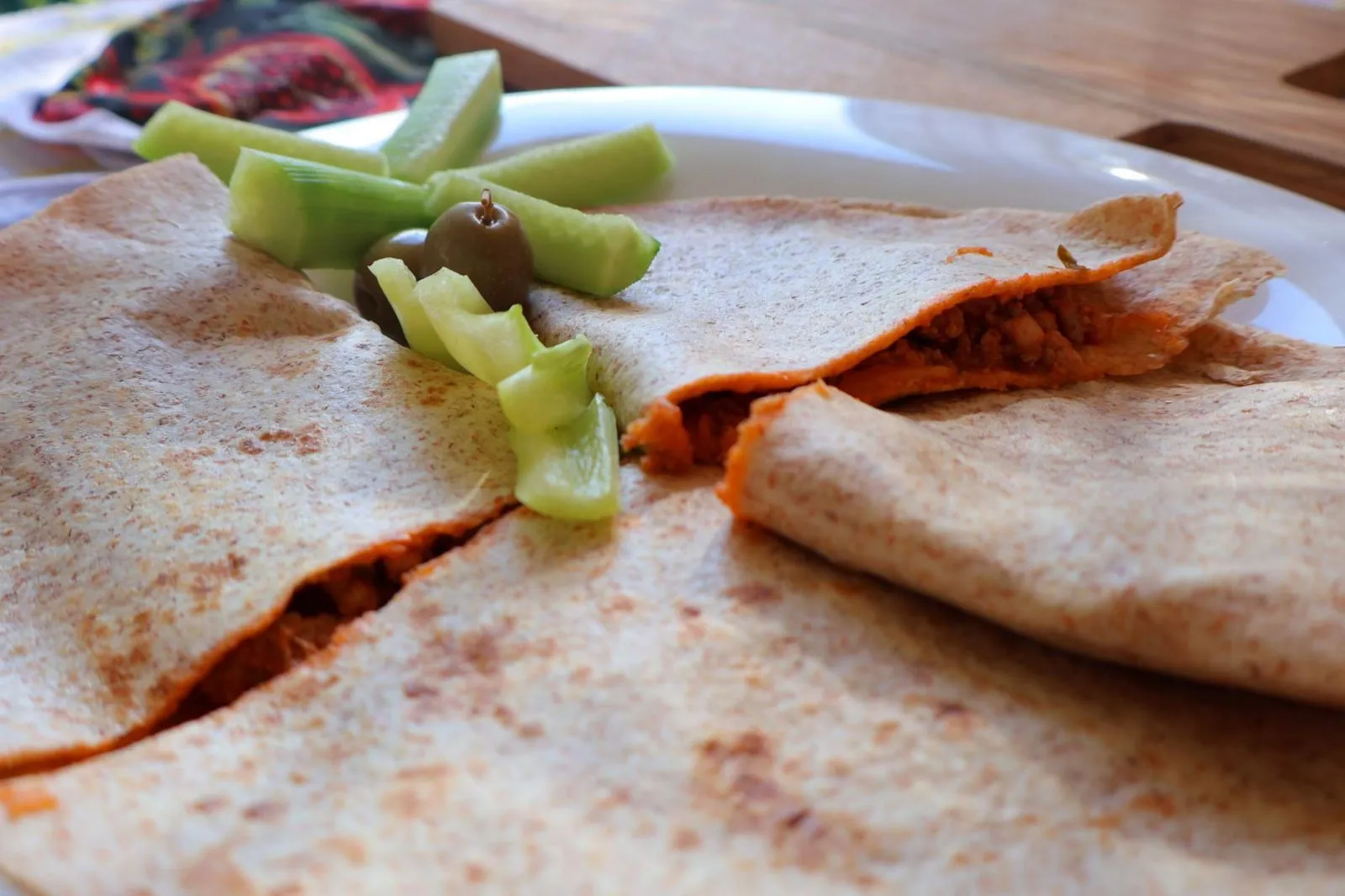 Folded wholewheat tortillas with a spiced filling, topped with cucumber and an olive